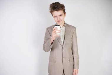 beyaz stüdyo arka plan üzerinde elinde kahve kağıt Fincan ile gri iş elbisesi genç erkek