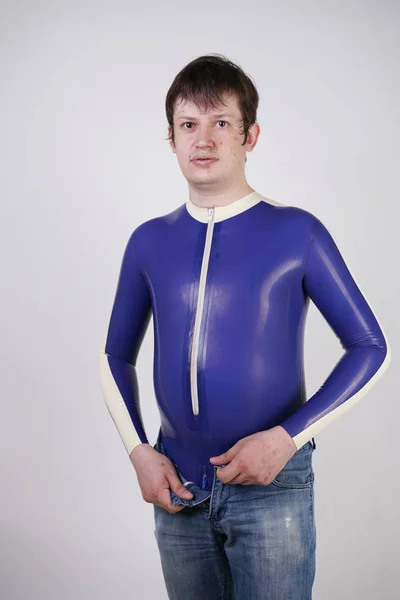 Caucasian nerd chubby man dressed in fashionable latex rubber fetish clothes on white background in Studio