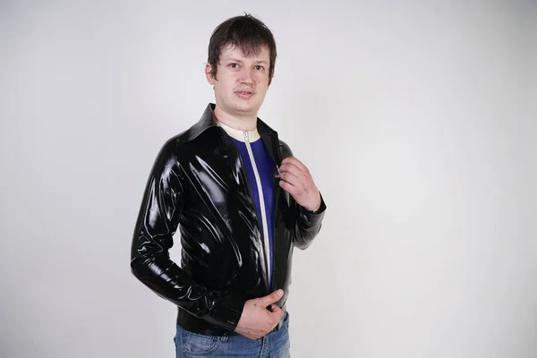 Caucasian nerd chubby man dressed in fashionable latex rubber fetish clothes on white background in Studio