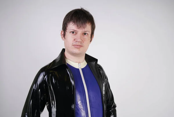 Caucasian nerd chubby man dressed in fashionable latex rubber fetish clothes on white background in Studio