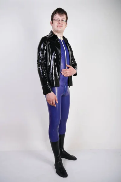 Caucasian nerd chubby man dressed in fashionable latex rubber fetish clothes on white background in Studio