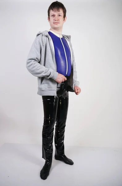 Caucasian nerd chubby man dressed in fashionable latex rubber fetish clothes on white background in Studio