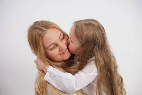 Real family of caucasian mother and daughter in white shirts in the studio background isolated