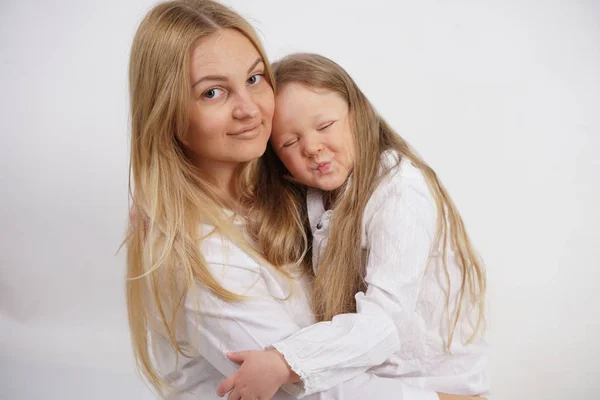 Real family of caucasian mother and daughter in white shirts in the studio background isolated