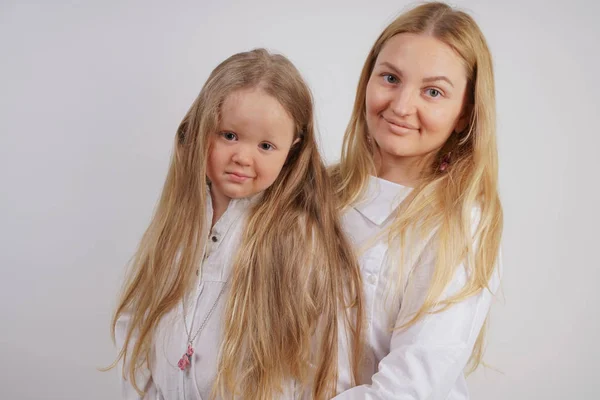 real family of caucasian mother and daughter in white shirts in the studio background