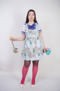 Stüdyo beyaz arka plan üzerinde anime okul üniforması ve mutfak önlüğü büyüleyici esmer pişirme kız