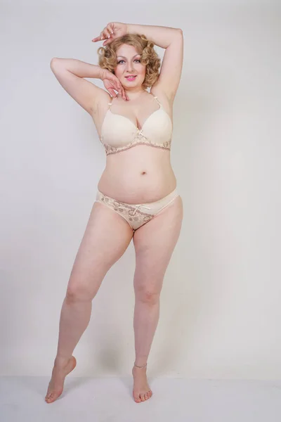 pretty caucasian chubby woman with plus size body and pale skin wearing underwear fashion lingerie on white studio background