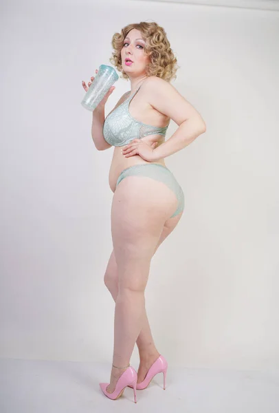 Pretty caucasian chubby woman with plus size body and pale skin wearing green lace sexy underwear on white studio background — Stock Photo, Image