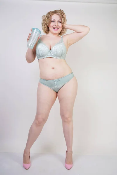 Mulher gordinha muito caucasiana com corpo plus size e pele pálida vestindo renda verde roupa interior sexy no fundo do estúdio branco — Fotografia de Stock