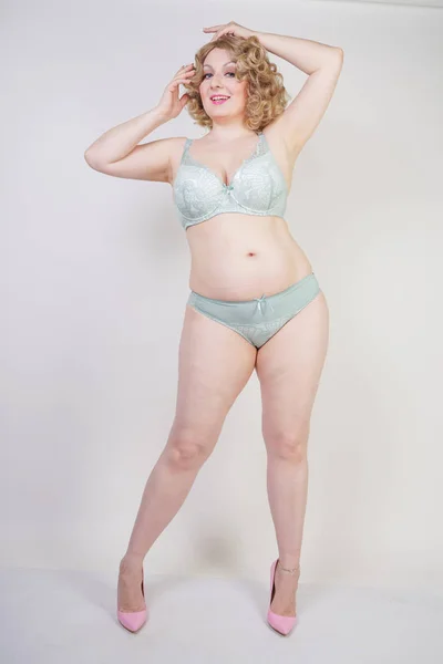 Pretty caucasian chubby woman with plus size body and pale skin wearing green lace sexy underwear on white studio background — Stock Photo, Image