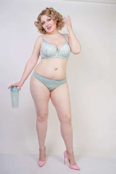Pěkná Kavkazská tloušlá žena s tělem a s bledou kůží v zeleném krajním sexy prádle na bílém studiovém pozadí — Stock fotografie