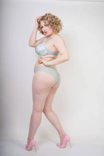 Mulher gordinha muito caucasiana com corpo plus size e pele pálida vestindo renda verde roupa interior sexy no fundo do estúdio branco — Fotografia de Stock