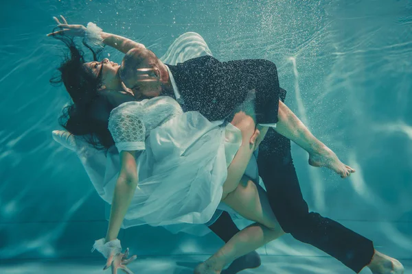 stock image beautiful romantic couple of bride and groom after wedding swimming gently under water and relax