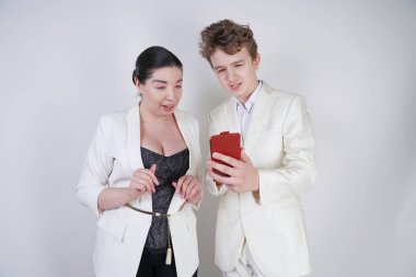 akıllı telefon ile poz veren, eğlenen ve selfie çeken iki komik arkadaş. yetişkin kız ve genç stüdyoda beyaz arka plan üzerinde kendi kendine fotoğraf çekmek.