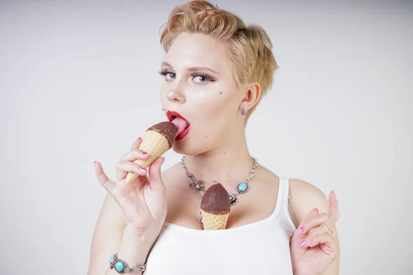 pretty caucasian blonde short hair girl eating tasty ice-cream with waffle cone and chocolate on white studio background
