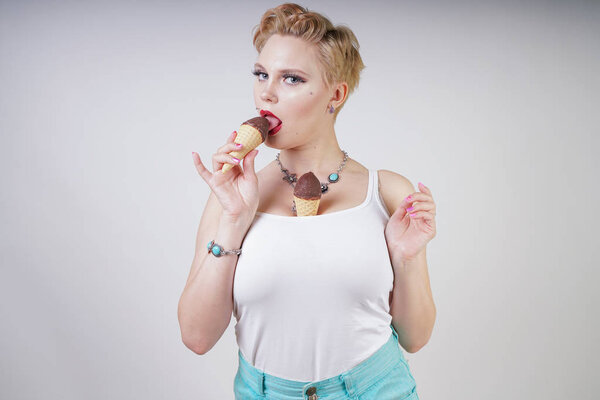 pretty caucasian blonde short hair girl eating tasty ice-cream with waffle cone and chocolate on white studio background