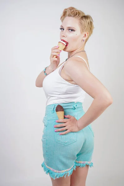 pretty caucasian blonde short hair girl eating tasty ice-cream with waffle cone and chocolate on white studio background