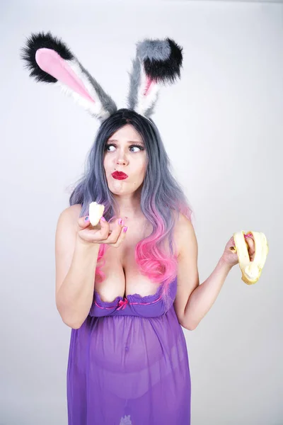 色情白种人胖女孩在透明内衣婴儿娃娃礼服与兔子耳朵享受香蕉和性调情的白色工作室背景 — 图库照片