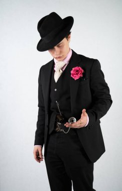 tek başına stüdyo beyaz bir arka planda elinde bir silah ile resmi bir takım elbise ve şapka genç adam