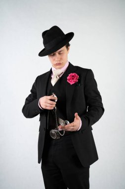 tek başına stüdyo beyaz bir arka planda elinde bir silah ile resmi bir takım elbise ve şapka genç adam