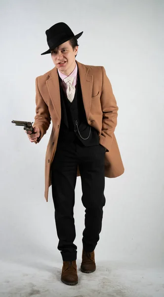 正式なスーツと帽子をかぶった若い男が 孤立したスタジオの白い背景に銃を手に — ストック写真