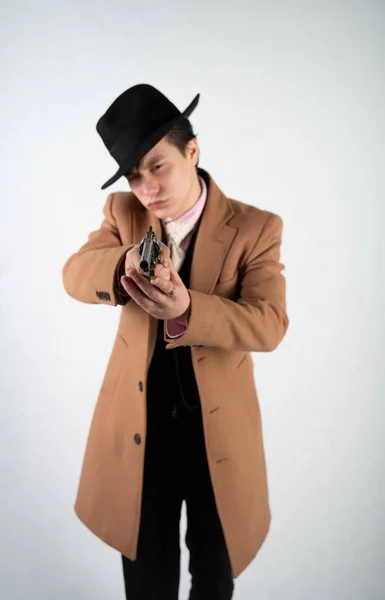 身着正式西装和帽子的年轻人手里拿着枪 在白色背景上独自在工作室里与 — 图库照片
