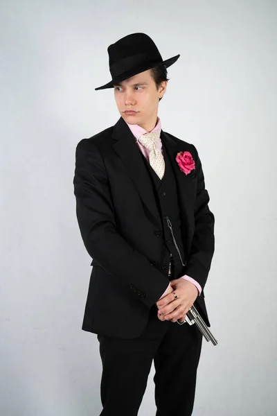 正式なスーツと帽子をかぶった若い男が 孤立したスタジオの白い背景に銃を手に — ストック写真