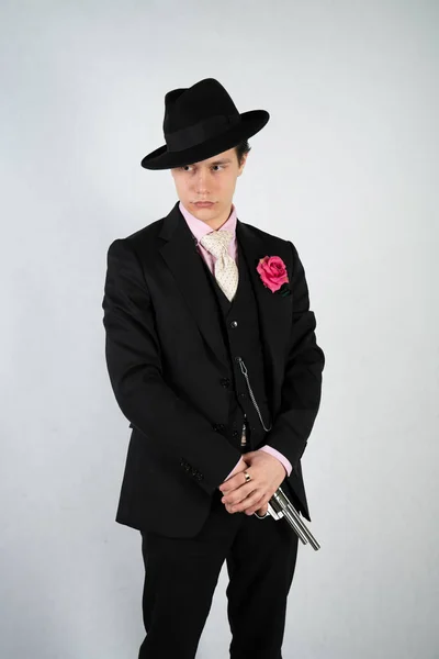 正式なスーツと帽子をかぶった若い男が スタジオだけで白い背景に銃を持った — ストック写真