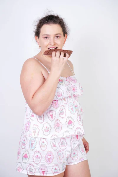 Zakřivená Žena Zábavním Pyžamu Čokoládovou Tyčí Bílém Pozadí Studiu — Stock fotografie