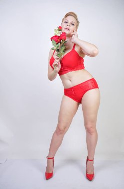 Kısa saçlı ve artı boyutunda beyaz stüdyo arka planda seksi kırmızı iç çamaşırı giyen soluk tenli güzel genç beyaz tombul kadın