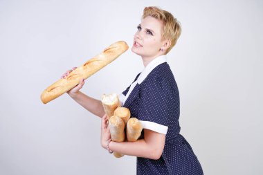 vintage polka nokta elbise giyen ve Studio beyaz bir arka plan üzerinde baget tutan sevimli kafkas pinup kız