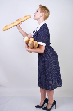 vintage polka nokta elbise giyen ve Studio beyaz bir arka plan üzerinde baget tutan sevimli kafkas pinup kız