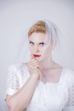 güneş tarzı etek ile uzun vintage gelinlik giyen kısa saçlı oldukça kıvrımlı yetişkin kadın. beyaz stüdyo arka plan tek başına peçe ile genç kafkas gelin.