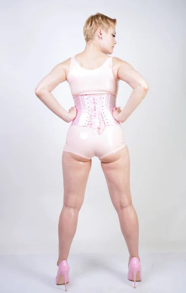 Zakřivená Sexy Krátkovlasá Dívka Růžovém Latexu Korzovými Stojany Bílém Pozadí — Stock fotografie