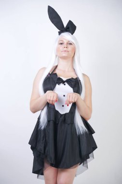Studio beyaz arka plan tavşan kostümü Bunny kulakları ile uzun beyaz saçlı sevimli kız. artı boyutu vücut ile bir kadın standları ve siyah bir elbise içinde moda pozlar yapmak.