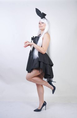 Studio beyaz arka plan tavşan kostümü Bunny kulakları ile uzun beyaz saçlı sevimli kız. artı boyutu vücut ile bir kadın standları ve siyah bir elbise içinde moda pozlar yapmak.