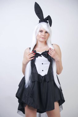 Studio beyaz arka plan tavşan kostümü Bunny kulakları ile uzun beyaz saçlı sevimli kız. artı boyutu vücut ile bir kadın standları ve siyah bir elbise içinde moda pozlar yapmak.