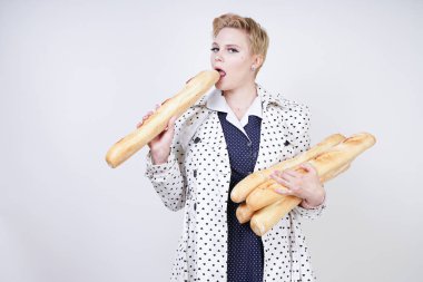 polka noktaları baget ile poz ve Studio beyaz bir arka plan üzerinde onları zevk ile bir bahar ceket kısa saçlı büyüleyici pinup kadın. artı retro giyim ekmek tutan boyutu kız.