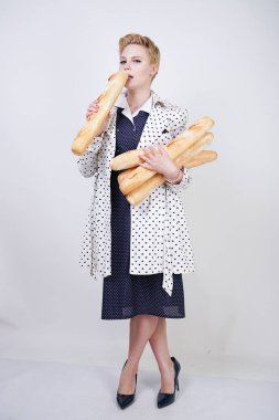 polka noktaları baget ile poz ve Studio beyaz bir arka plan üzerinde onları zevk ile bir bahar ceket kısa saçlı büyüleyici pinup kadın. artı retro giyim ekmek tutan boyutu kız.