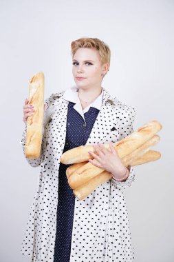 polka noktaları baget ile poz ve Studio beyaz bir arka plan üzerinde onları zevk ile bir bahar ceket kısa saçlı büyüleyici pinup kadın. artı retro giyim ekmek tutan boyutu kız.