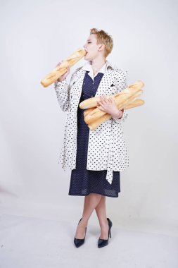 polka noktaları baget ile poz ve Studio beyaz bir arka plan üzerinde onları zevk ile bir bahar ceket kısa saçlı büyüleyici pinup kadın. artı retro giyim ekmek tutan boyutu kız.