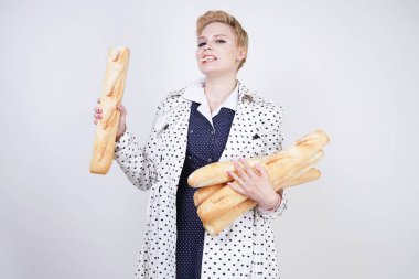 polka noktaları baget ile poz ve Studio beyaz bir arka plan üzerinde onları zevk ile bir bahar ceket kısa saçlı büyüleyici pinup kadın. artı retro giyim ekmek tutan boyutu kız.