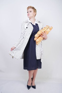 polka noktaları baget ile poz ve Studio beyaz bir arka plan üzerinde onları zevk ile bir bahar ceket kısa saçlı büyüleyici pinup kadın. artı retro giyim ekmek tutan boyutu kız.