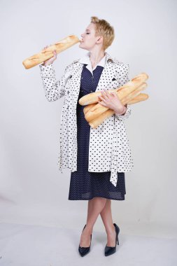 polka noktaları baget ile poz ve Studio beyaz bir arka plan üzerinde onları zevk ile bir bahar ceket kısa saçlı büyüleyici pinup kadın. artı retro giyim ekmek tutan boyutu kız.