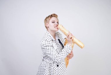 polka noktaları baget ile poz ve Studio beyaz bir arka plan üzerinde onları zevk ile bir bahar ceket kısa saçlı büyüleyici pinup kadın. artı retro giyim ekmek tutan boyutu kız.