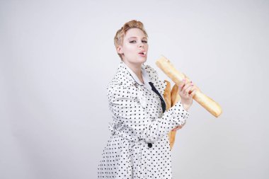 polka noktaları baget ile poz ve Studio beyaz bir arka plan üzerinde onları zevk ile bir bahar ceket kısa saçlı büyüleyici pinup kadın. artı retro giyim ekmek tutan boyutu kız.