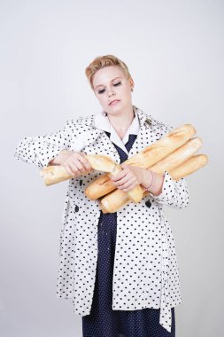 polka noktaları baget ile poz ve Studio beyaz bir arka plan üzerinde onları zevk ile bir bahar ceket kısa saçlı büyüleyici pinup kadın. artı retro giyim ekmek tutan boyutu kız.