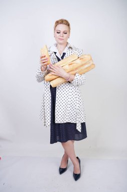 polka noktaları baget ile poz ve Studio beyaz bir arka plan üzerinde onları zevk ile bir bahar ceket kısa saçlı büyüleyici pinup kadın. artı retro giyim ekmek tutan boyutu kız.