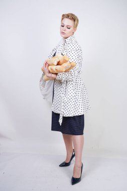 polka noktaları baget ile poz ve Studio beyaz bir arka plan üzerinde onları zevk ile bir bahar ceket kısa saçlı büyüleyici pinup kadın. artı retro giyim ekmek tutan boyutu kız.