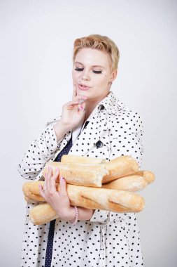 polka noktaları baget ile poz ve Studio beyaz bir arka plan üzerinde onları zevk ile bir bahar ceket kısa saçlı büyüleyici pinup kadın. artı retro giyim ekmek tutan boyutu kız.